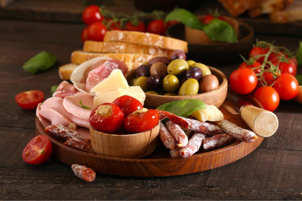 Mediterraner Antipasti Platte mit Salami, Gefüllten Tomaten, Oliven und italienisches Brot
